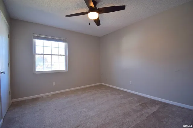 an empty room with a window and a fan