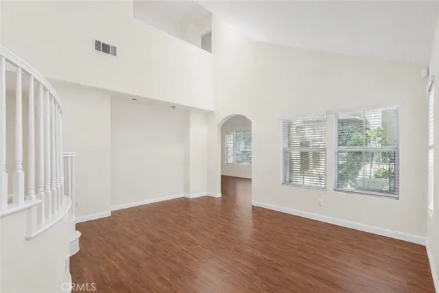 an empty room with wooden floor fireplace and windows