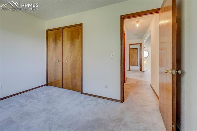 18715 Spring Valley Road Monument, CO 80132 - Photo 26 of 35 Unfurnished bedroom with a textured ceiling, a closet, and light colored carpet