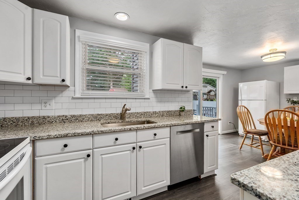 12 Cypress Road Natick, MA 01760 - Photo 10 of 41 a kitchen with stainless steel appliances granite countertop a stove a sink dishwasher and white cabinets with wooden floor