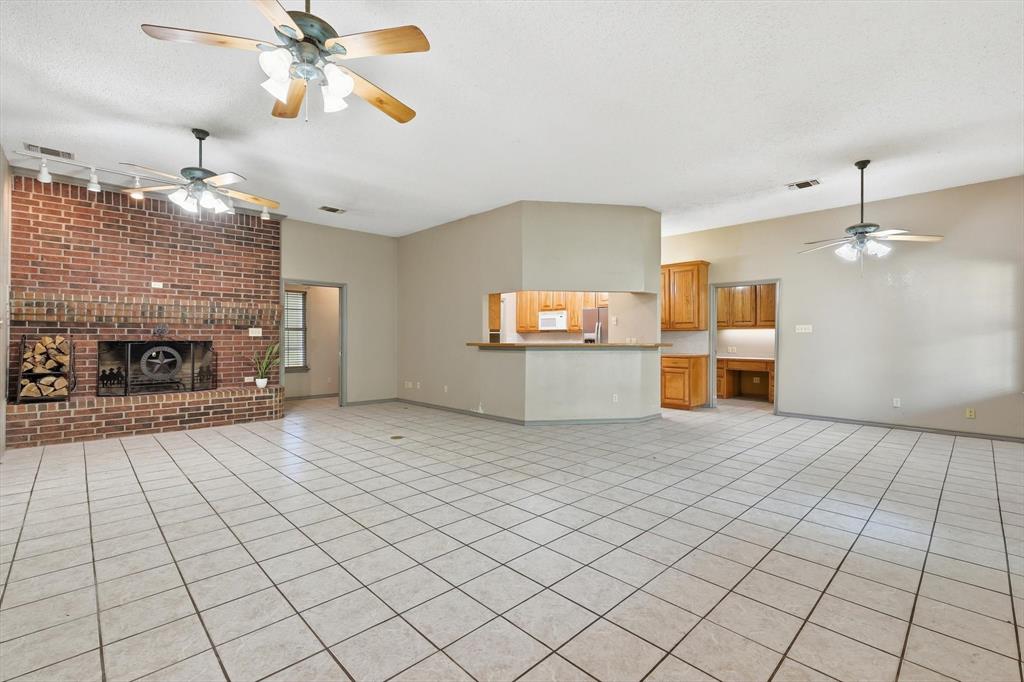 135 Private Road 2202 Decatur, TX 76234 - Photo 5 of 40 Unfurnished living room with a ceiling fan, light tile patterned flooring, a brick fireplace, rail lighting, and a textured ceiling