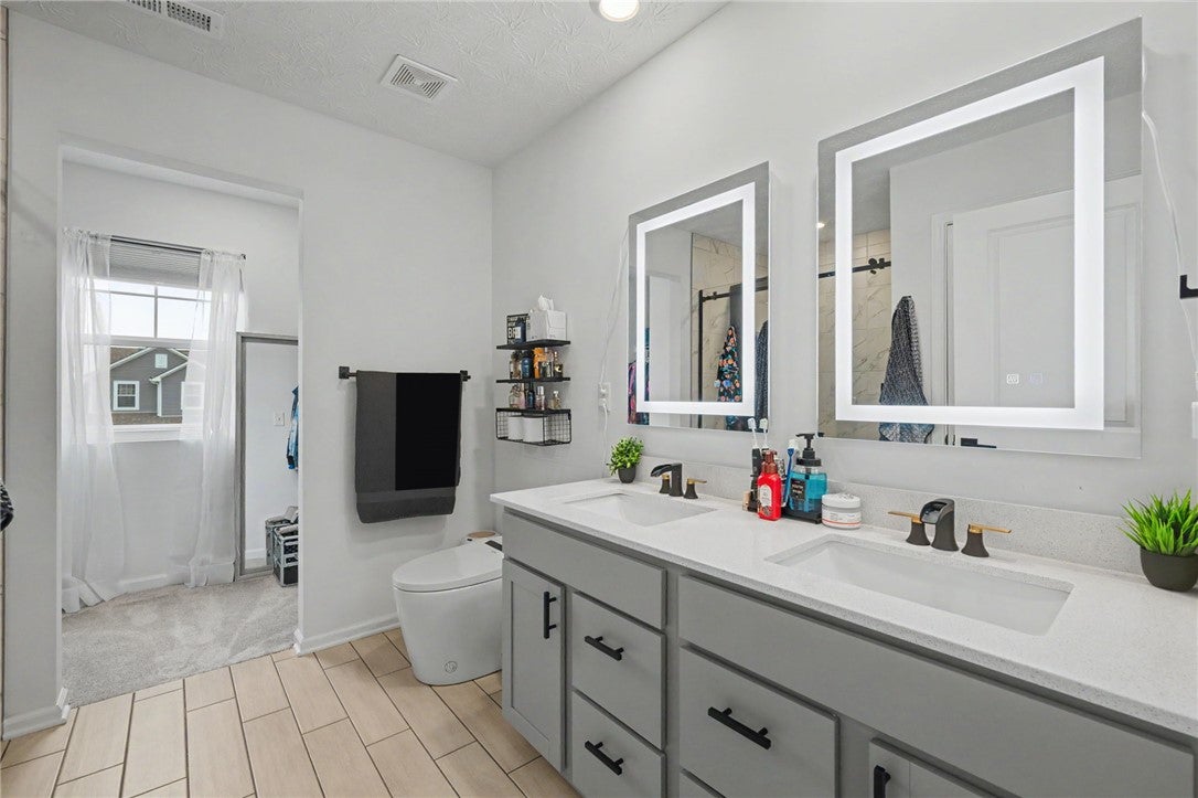 3011 Falls Road Clayton, OH 45315 - Photo 40 of 66 A well-lit primary bathroom featuring a double vanity with ample counter space and modern fixtures.