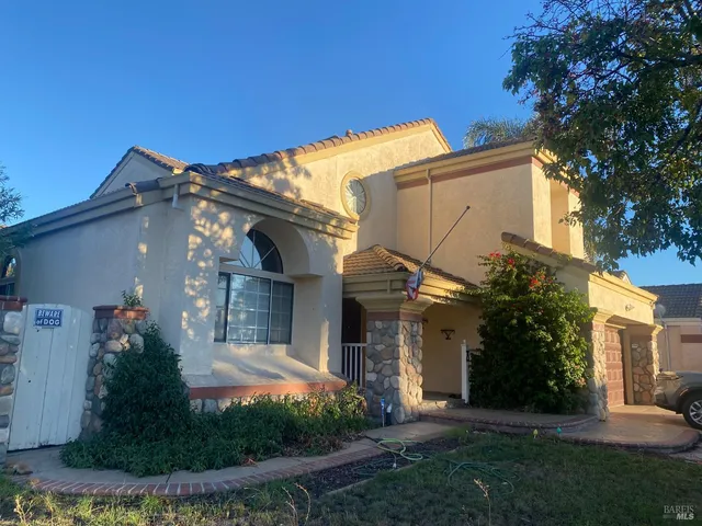 a view of a white house with a small yard and a large tree