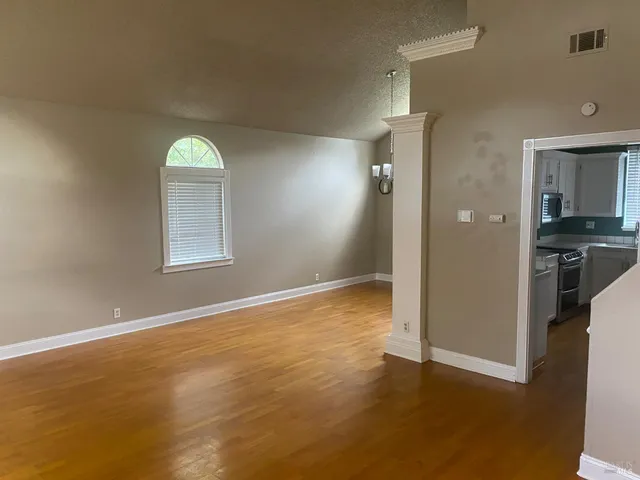 a view of empty room with window and wooden floor