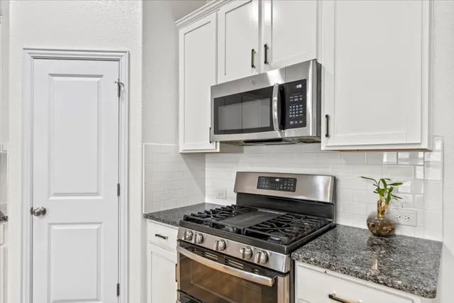 a kitchen with stainless steel appliances granite countertop white cabinets and a stove top oven