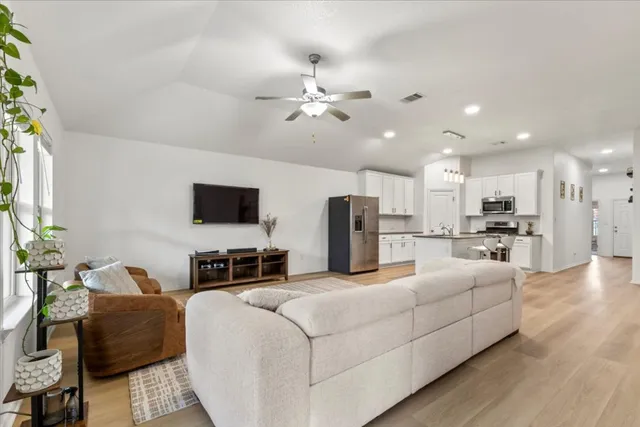 a living room with furniture kitchen view and a flat screen tv