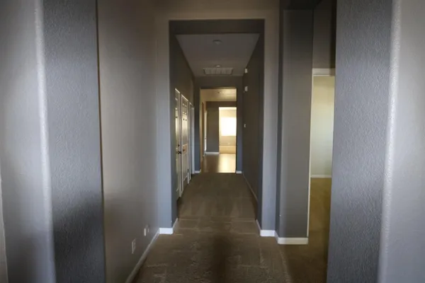 a view of a hallway with wooden floor and a bathroom