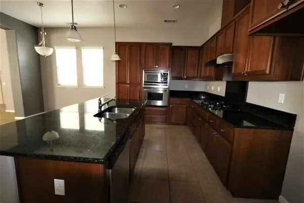 a kitchen with kitchen island granite countertop stainless steel appliances a sink stove refrigerator and cabinets
