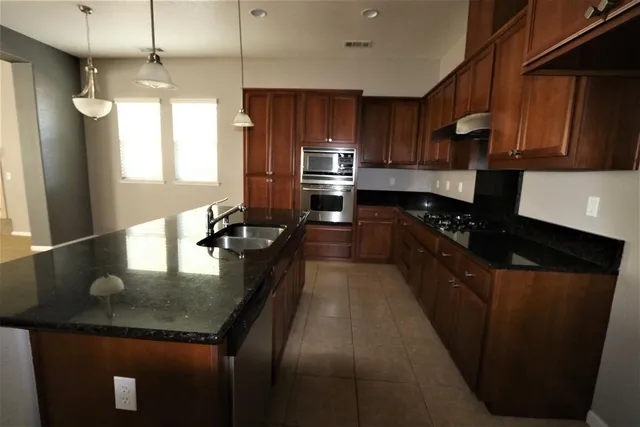 a kitchen with kitchen island granite countertop stainless steel appliances a sink stove refrigerator and cabinets