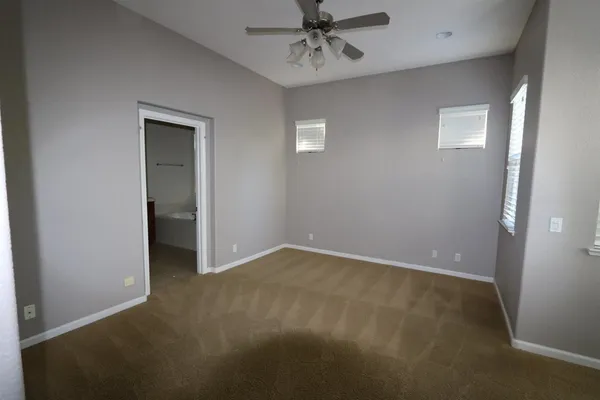 an empty room with windows and fan