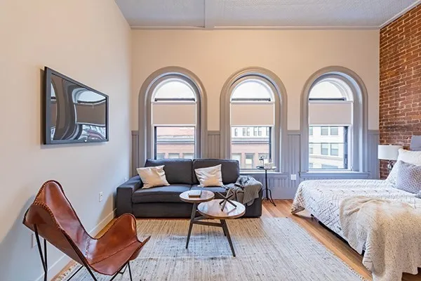 a spacious bedroom with a bed a couch chair and a large window