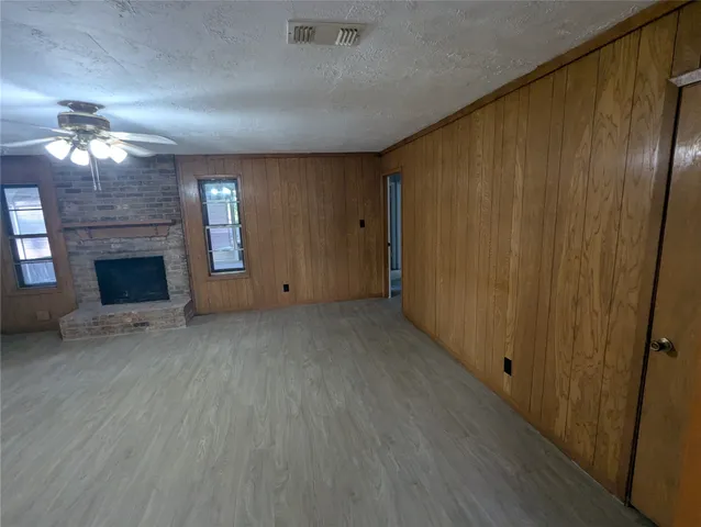 an empty room with windows fireplace and a kitchen view