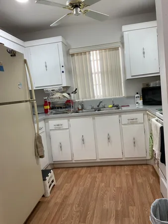 a kitchen with stainless steel appliances granite countertop a sink a stove a refrigerator with white cabinets and wooden floor