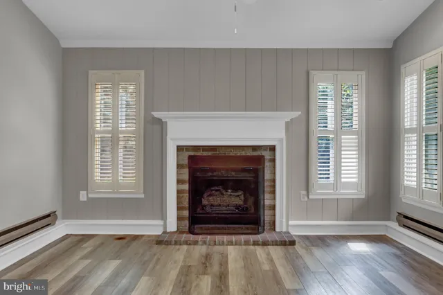 a view of an empty room with exposed radiator and a fireplace