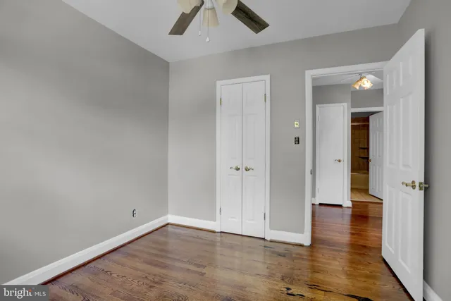 an empty room with wooden floor and ceiling fan