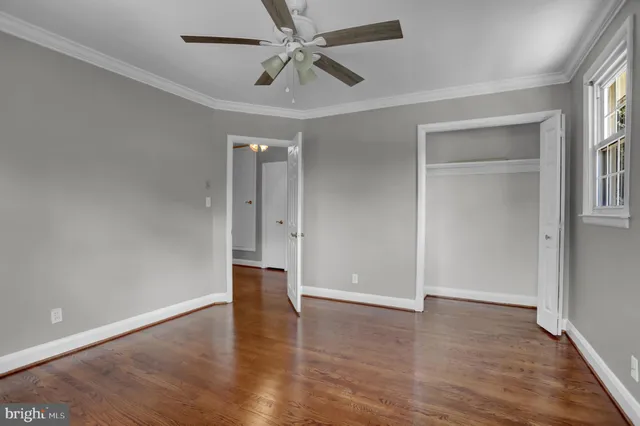 an empty room with wooden floor closet and windows