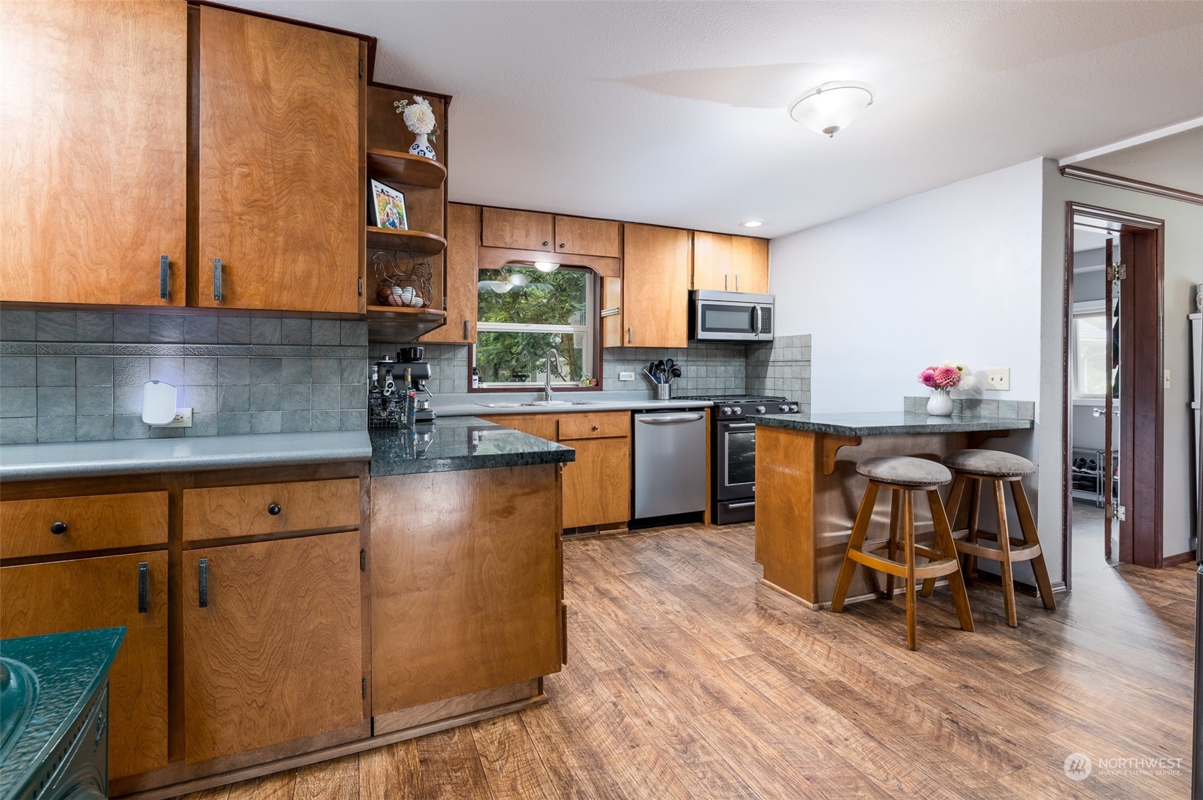 6283 Noon Road Everson, WA 98247 - Photo 15 of 40 a kitchen with stainless steel appliances granite countertop a stove top oven a sink dishwasher a dining table and chairs with wooden floor