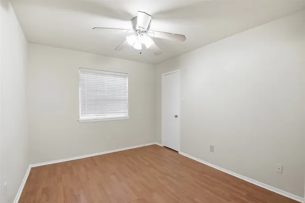 an empty room with a chandelier fan and windows