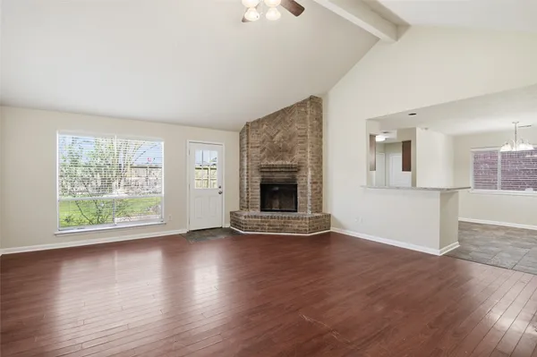 an empty room with wooden floor fire place and windows