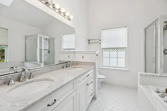 a bathroom with a granite countertop double vanity sink a mirror and a bathtub