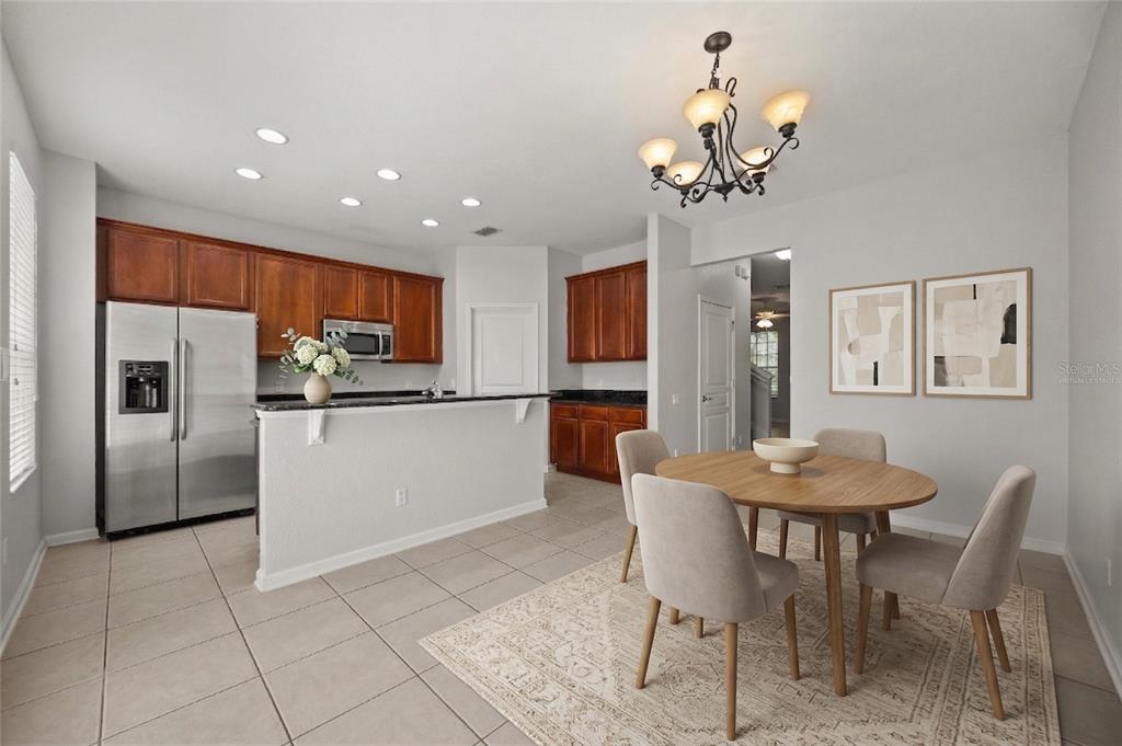 7719 Anselmo Lane Windermere, FL 34786 - Photo 7 of 31 a kitchen with stainless steel appliances granite countertop a refrigerator a sink dishwasher a dining table and chairs with wooden floor