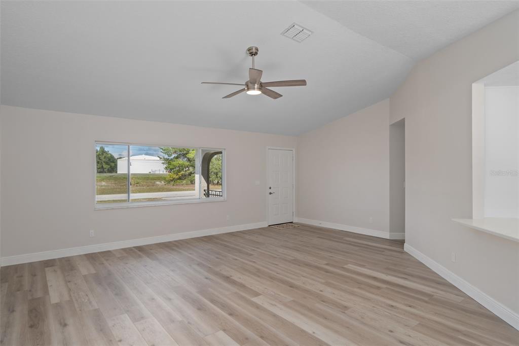 10352 Brentlawn Street Spring Hill, FL 34608 - Photo 13 of 35 an empty room with wooden floor ceiling fan and windows