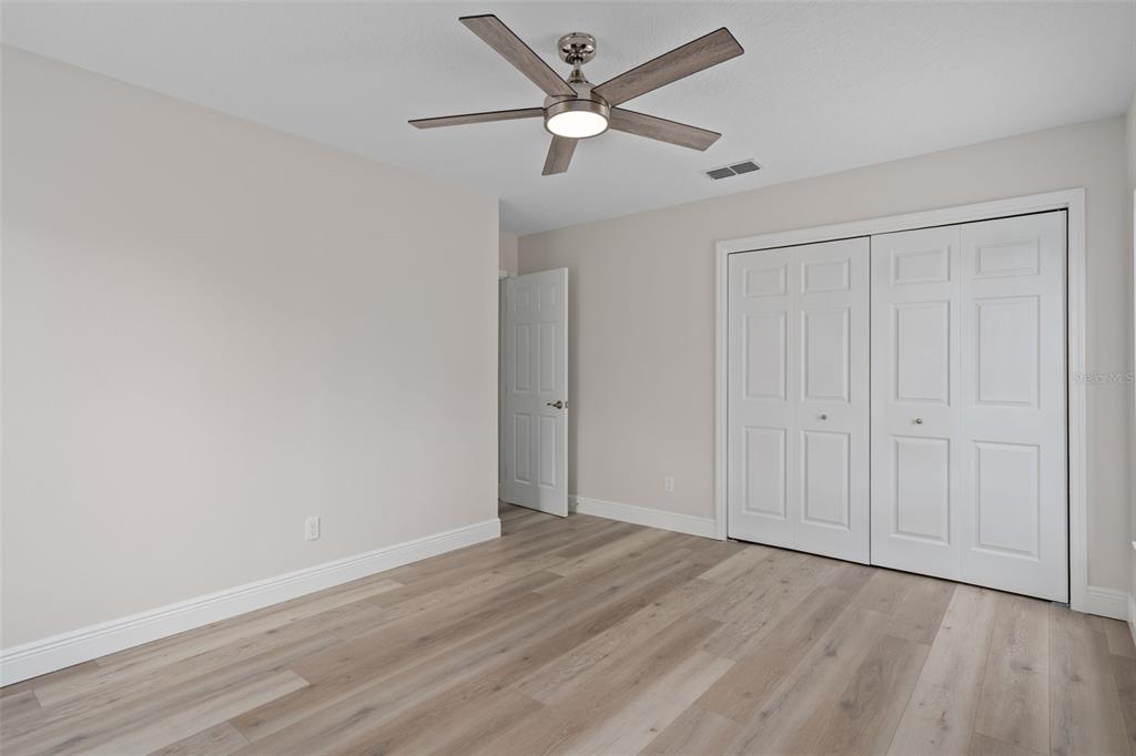 10352 Brentlawn Street Spring Hill, FL 34608 - Photo 16 of 35 an empty room with wooden floor ceiling fan and windows