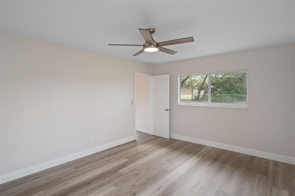 10352 Brentlawn Street Spring Hill, FL 34608 - Photo 23 of 35 an empty room with wooden floor ceiling fan and windows