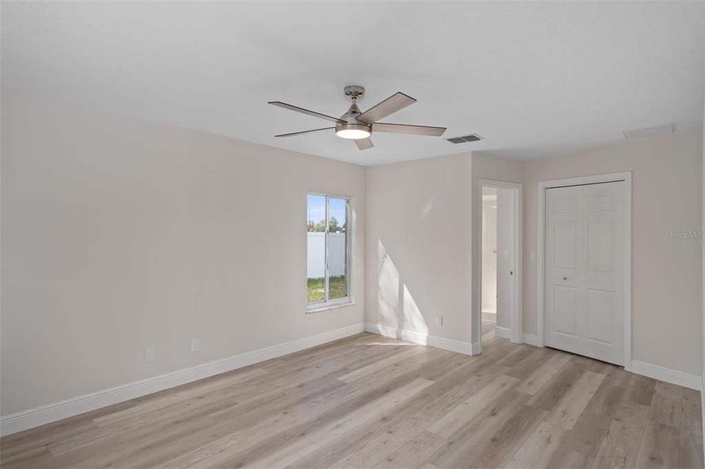 10352 Brentlawn Street Spring Hill, FL 34608 - Photo 6 of 35 an empty room with wooden floor ceiling fan and windows