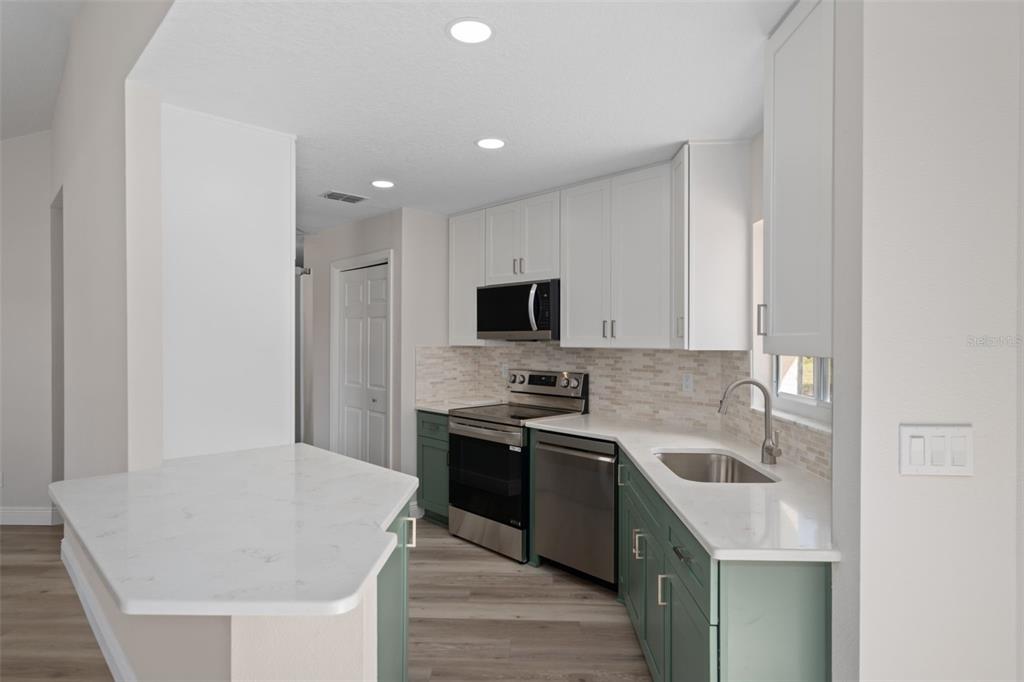 10352 Brentlawn Street Spring Hill, FL 34608 - Photo 9 of 35 a kitchen with stainless steel appliances granite countertop a sink stove and refrigerator