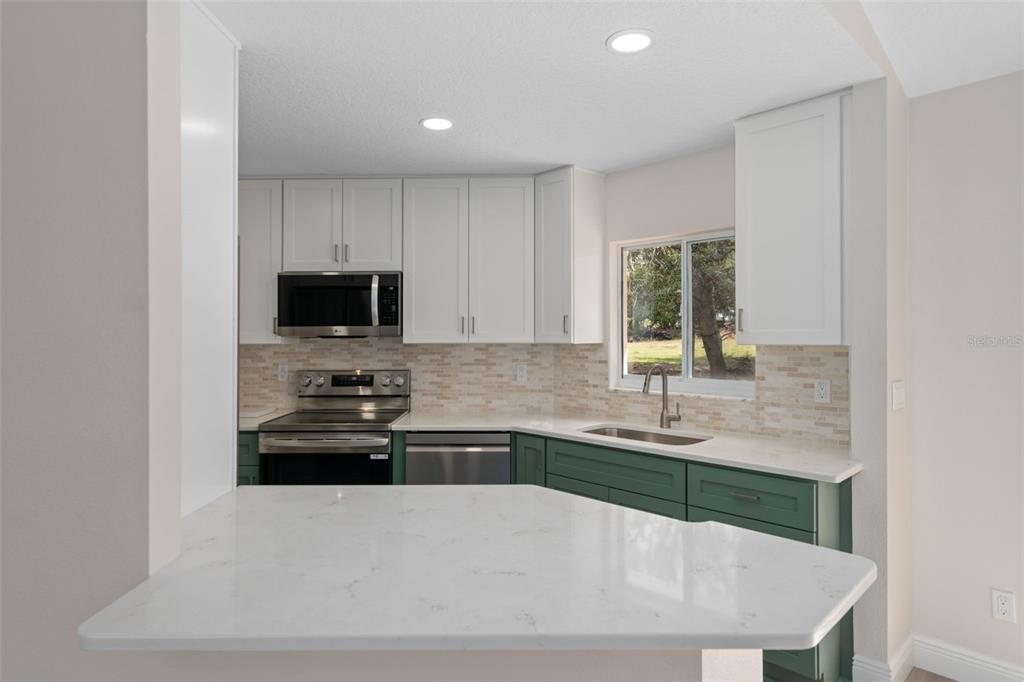 10352 Brentlawn Street Spring Hill, FL 34608 - Photo 10 of 35 a kitchen with stainless steel appliances a sink a stove a microwave a sink and cabinets