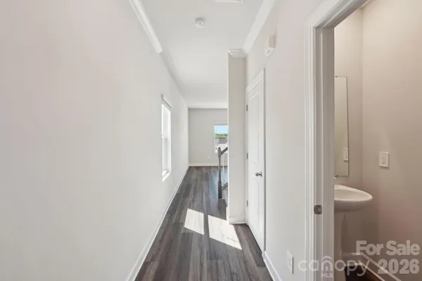 a view of a hallway with wooden floor and a bathroom
