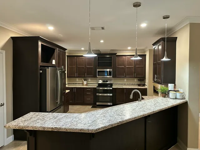 a kitchen with kitchen island granite countertop a refrigerator a sink a counter space and wooden floor