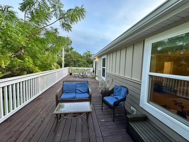 a balcony with wooden floor table and chairs