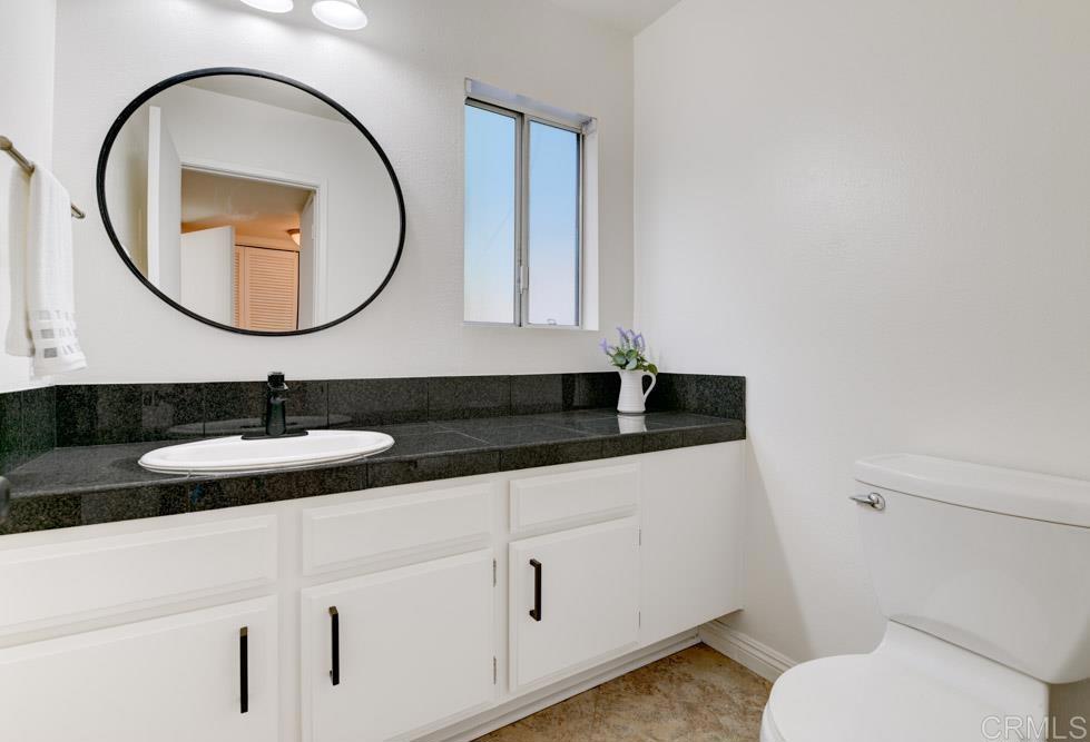3573 Evening Canyon Road Oceanside, CA 92056 - Photo 16 of 45 a bathroom with a granite countertop toilet a sink and a mirror