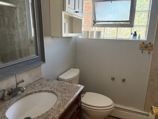 a bathroom with a granite countertop toilet a sink and a mirror