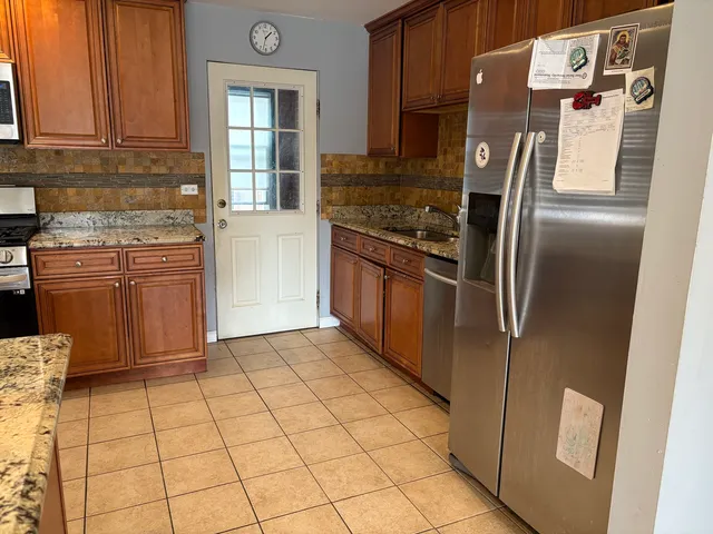 a kitchen with stainless steel appliances granite countertop a refrigerator and a stove top oven