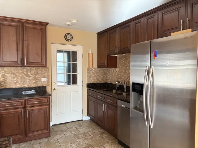 a kitchen with granite countertop a refrigerator and a stove top oven