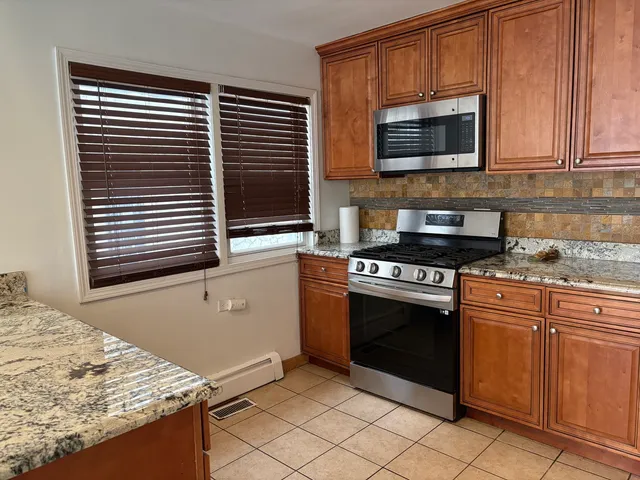 a kitchen with granite countertop a stove top oven microwave and cabinets