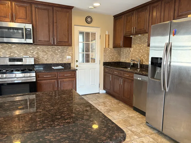 a kitchen with granite countertop a refrigerator stove and cabinets