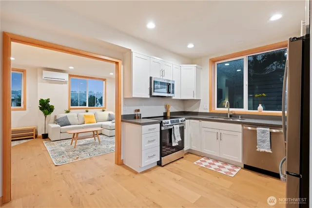 a kitchen with stainless steel appliances granite countertop a stove top oven a sink dishwasher and white cabinets with wooden floor