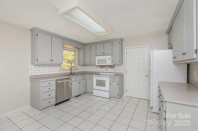 a kitchen with white cabinets a stove a sink and a window