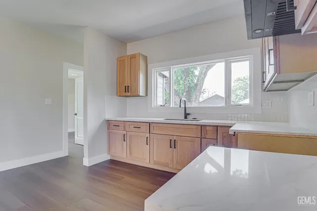 a white kitchen with wooden floors and sink