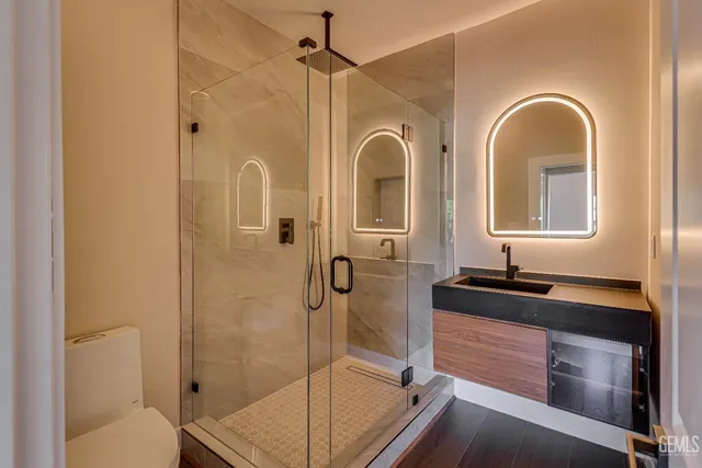 a bathroom with a granite countertop sink mirror shower and toilet
