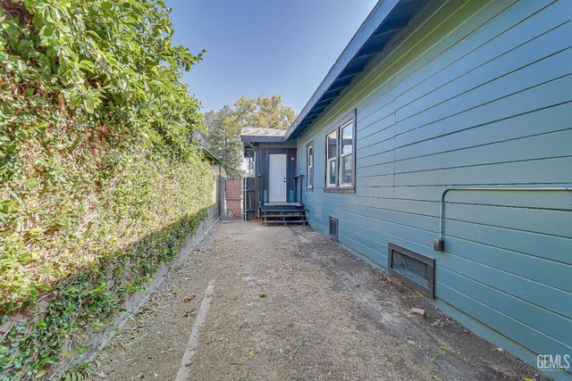a view of a backyard with plants and large tree