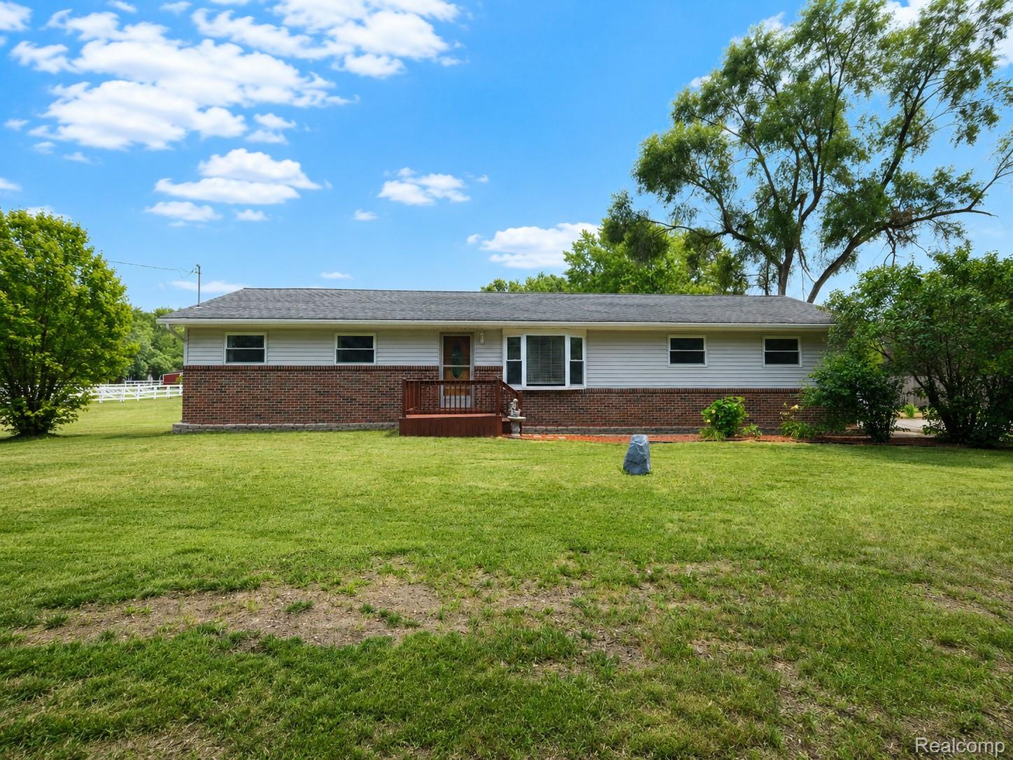 Ranch-style residence featuring a brick and siding exterior, a front deck, and a bay window