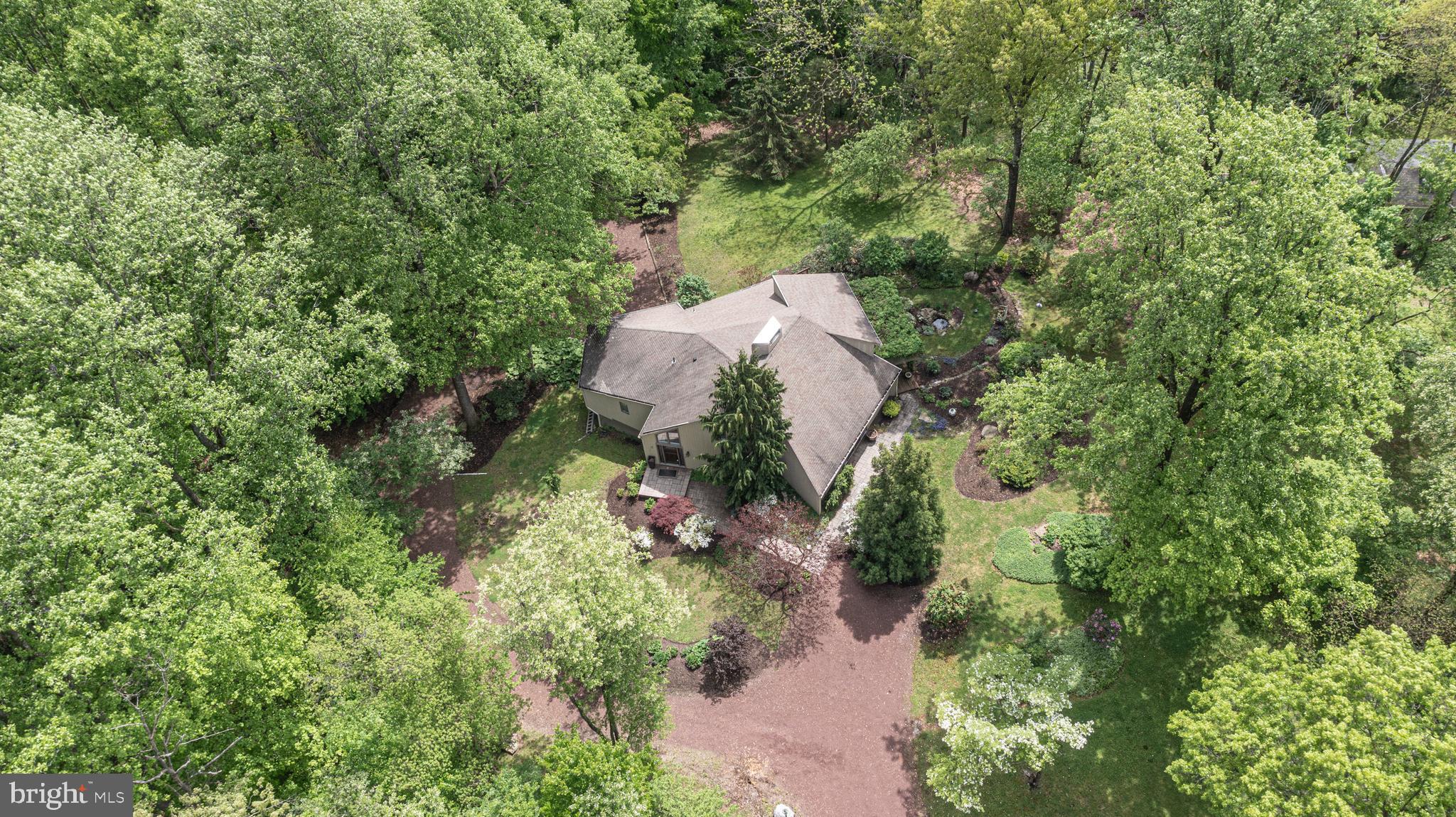 an aerial view of a house with a yard and covered with trees