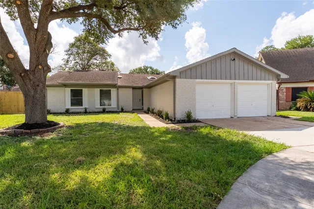 a view of a house with a yard and large tree