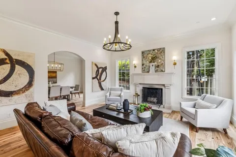 a kitchen with kitchen island granite countertop a stove a sink a dining table and chairs with wooden floor