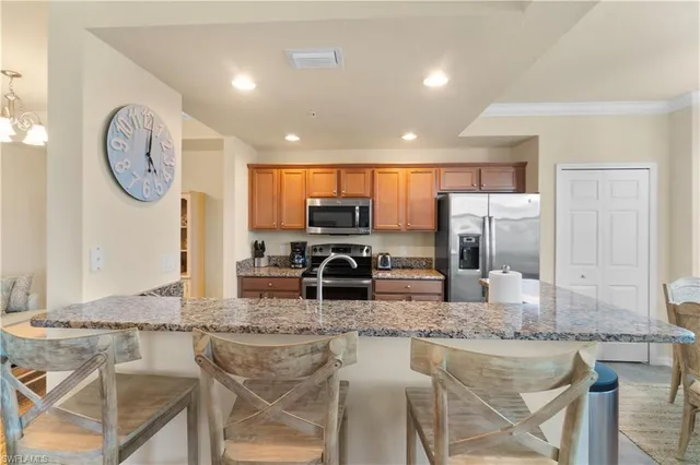 a kitchen with stainless steel appliances granite countertop a stove top oven a sink a dining table and chairs
